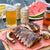 Outdoor setting with ribs, beer, and watermelon on a wooden table.